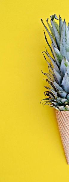 La tige d'un ananas dans un cône de crème glacée sur un fond monochrome comme symbole de la crème glacée à l'ananas comme rafraîchissement fruité en été
 - Photo, image