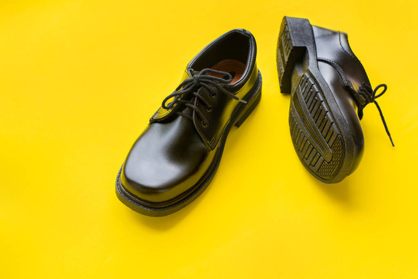 Black leather shoes yellow background top view - 写真・画像