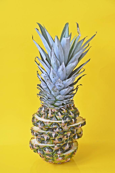 slices of a pineapple make up a whole pineapple in front of a solid background with space for text or objects - Foto, imagen