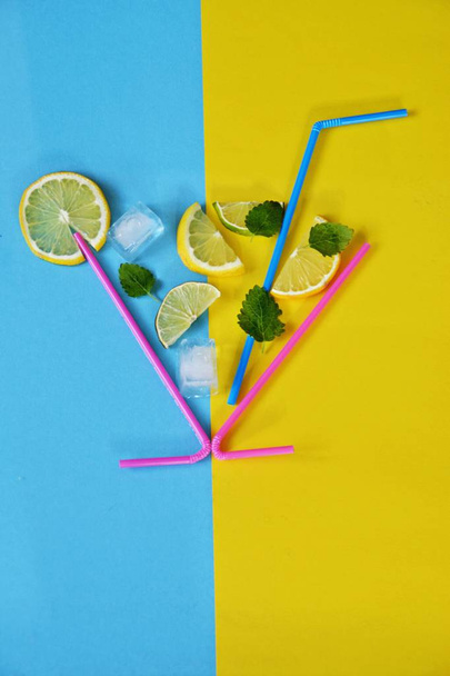 Концепція літнього напою - Соломка складає склянку в лимонах, вапняках, м'ятних і крижаних плитах на барвистому фоні - Анотація літнього відпочинку з місцем для тексту
  - Фото, зображення