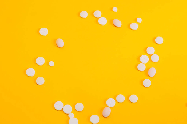 Different pills and vitamins are scattered on a yellow background. space for text, closeup - Foto, Imagen