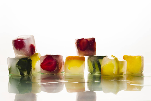 Ijsblokjes met fruit op een heldere witte achtergrond. Het concept van hete zomer, dessert, ijs. Platte lay, bovenaanzicht - Foto, afbeelding