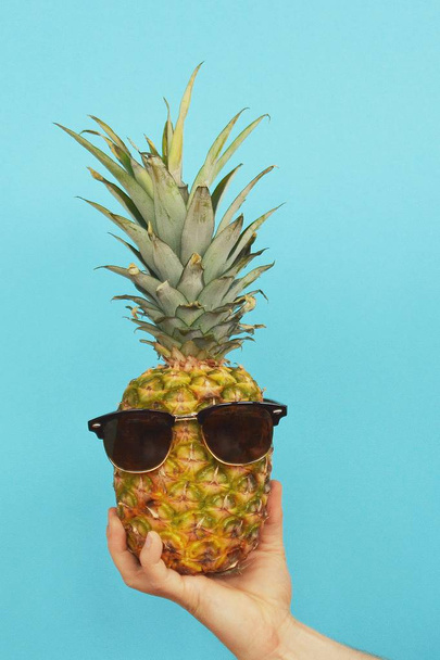 holding a pineapple with sunglasses in the hand  - Foto, imagen