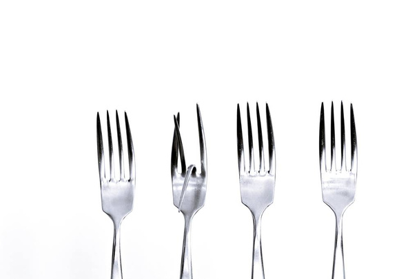 Three normal and one bent fork in a row as a symbol that being exceptional is not equate to being useful and meaningful - Concept with Forks - One is different than all the others  - Photo, Image