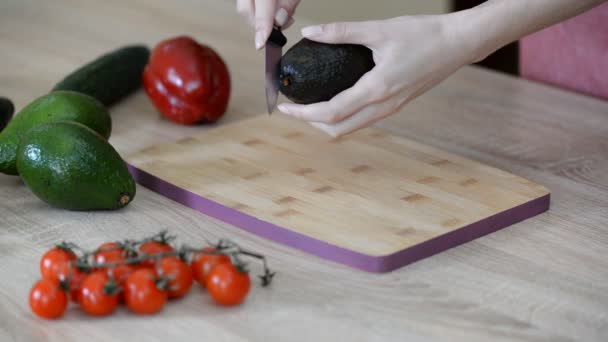 Slicing fresh avocado on a wood cutting board. - Кадри, відео