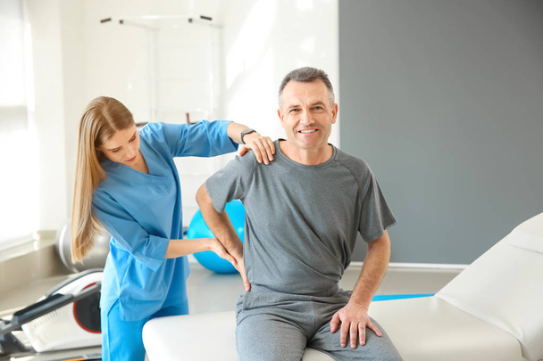 Physiotherapist working with mature patient in rehabilitation center - Fotó, kép