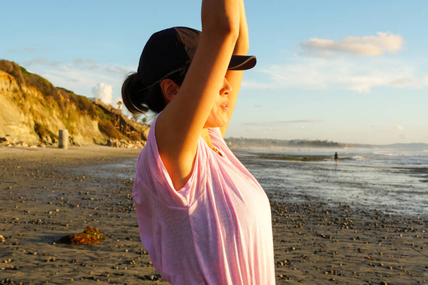 Азиат молодая здоровая женщина смотрит далеко во время заката на пляже. Сильная уверенность женщины под закатом на берегу моря
.  - Фото, изображение
