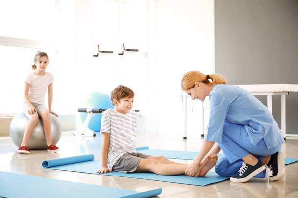 Physiotherapist working with little boy in rehabilitation center - Фото, изображение