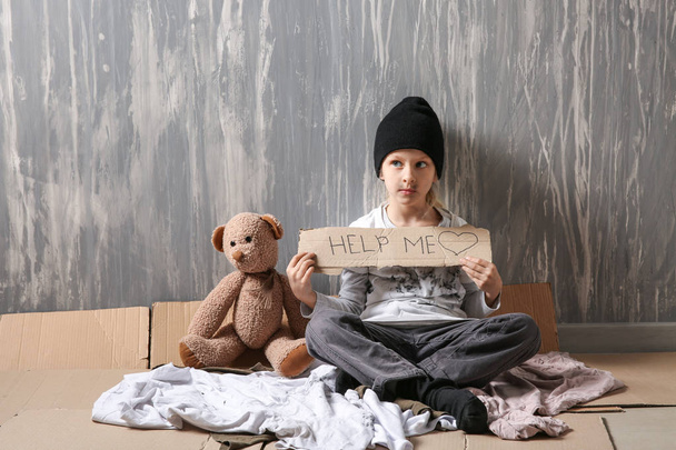 Бездомна дівчинка благає допомоги біля стіни
 - Фото, зображення
