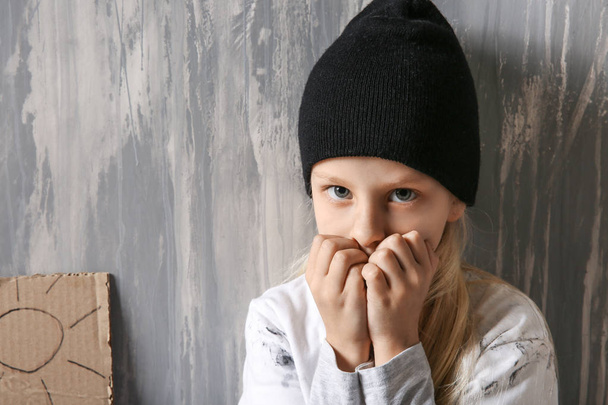 Бездомная маленькая девочка возле серой стены
 - Фото, изображение