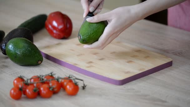 Het snijden van verse avocado op een houten snijplank. - Video