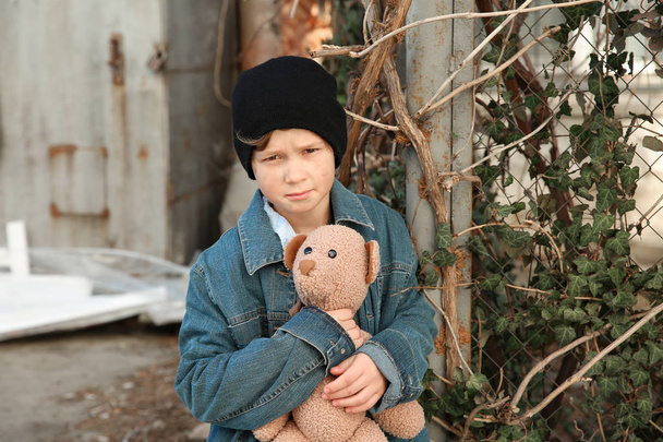Piccolo ragazzo senzatetto con orsacchiotto all'aperto
 - Foto, immagini
