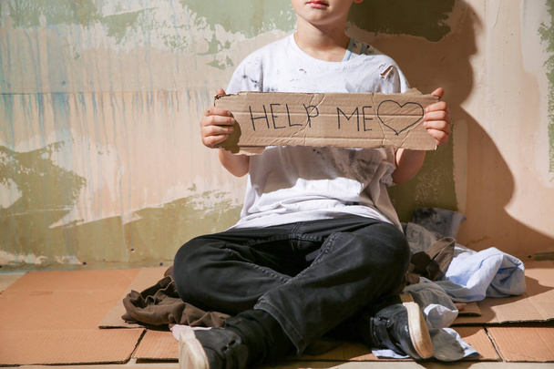 壁の近くで助けを求めるホームレスの少年 - 写真・画像