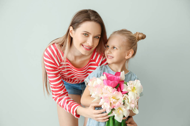 Menina e sua mãe com buquê de tulipas no fundo claro
 - Foto, Imagem