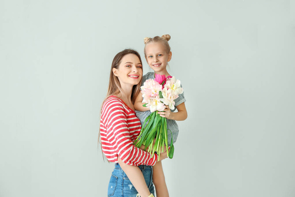 Маленькая девочка и ее мать с букетом тюльпанов на светлом фоне
 - Фото, изображение