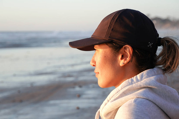 Азиат молодая здоровая женщина смотрит далеко во время заката на пляже. Сильная уверенность женщины под закатом на берегу моря
.  - Фото, изображение