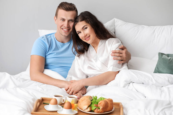 Jeune couple mignon prenant le petit déjeuner au lit
 - Photo, image