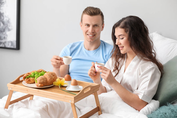 Χαριτωμένο νεαρό ζευγάρι που έχει πρωινό στο κρεβάτι - Φωτογραφία, εικόνα