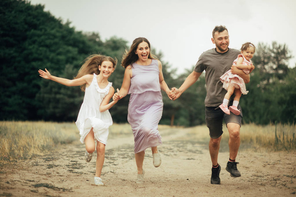 Η ευτυχισμένη οικογένεια διασκεδάζει, τρέχει και γελάει σε μια βόλτα. - Φωτογραφία, εικόνα