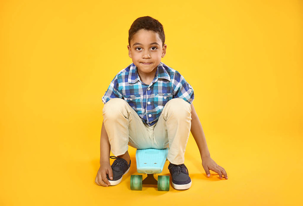 Portrait of cute little boy with skateboard on color background - Photo, Image