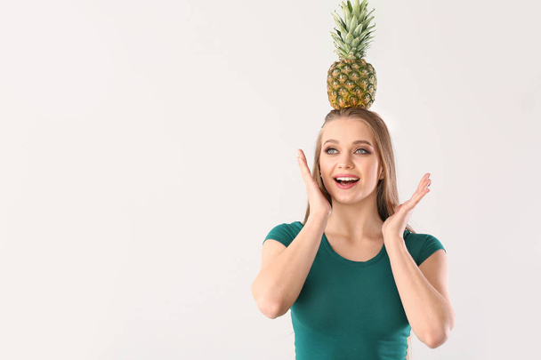 Удивлённая молодая женщина с ананасом на белом фоне
 - Фото, изображение