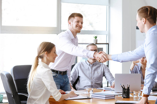 Młodzi biznesmeni drżenie rąk na spotkaniu w biurze - Zdjęcie, obraz