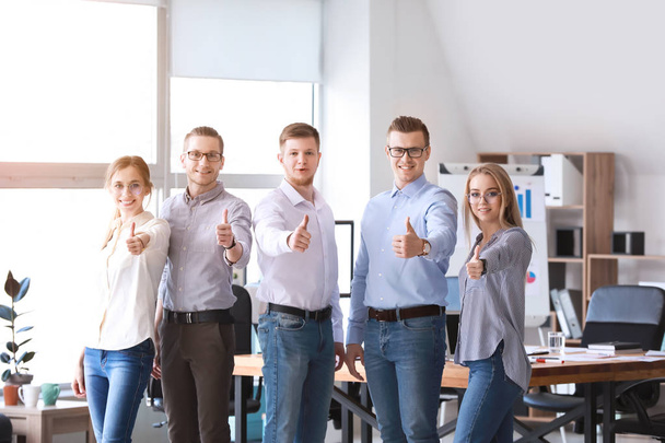 オフィスで親指のジェスチャーを示す若いビジネスマンのグループ - 写真・画像