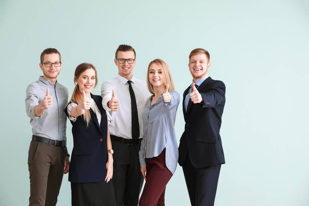 Grupo de jóvenes empresarios que muestran un gesto de pulgar hacia arriba sobre fondo claro
 - Foto, imagen