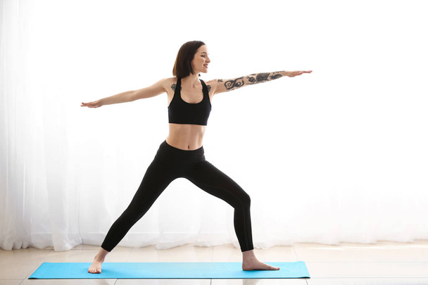 Beautiful tattooed woman practicing yoga at home - Photo, Image