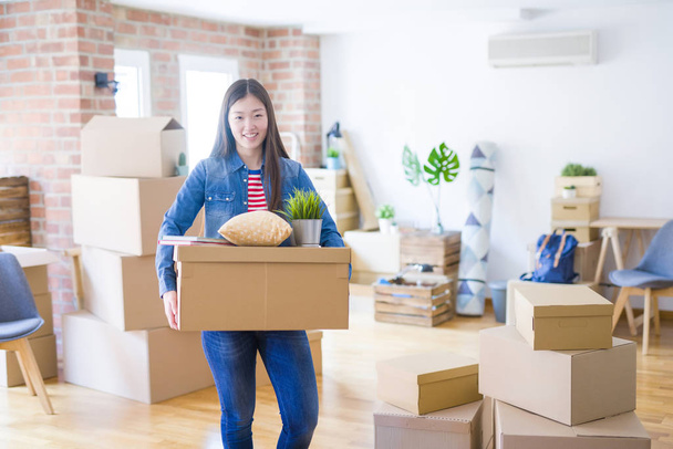 Beautiful asian young woman holding boxes, smiling happy moving  - Photo, Image