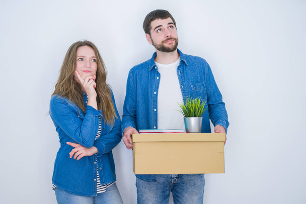 白い孤立した背景の上に新しい家に移動する段ボール箱を持つ若いカップルは、質問を考え、非常に混乱したアイデア - 写真・画像
