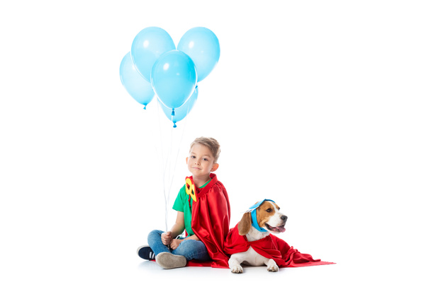 preschooler gyermek és Beagle kutya vörös hős köpeny a kék fél léggömbök fehér - Fotó, kép