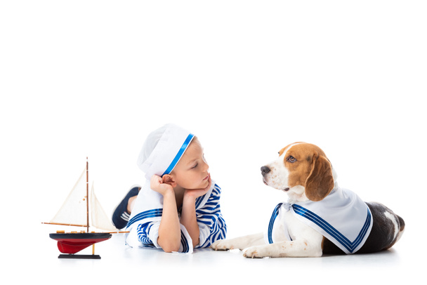preschooler child in sailor costume with toy ship and beagle dog on white - Fotoğraf, Görsel