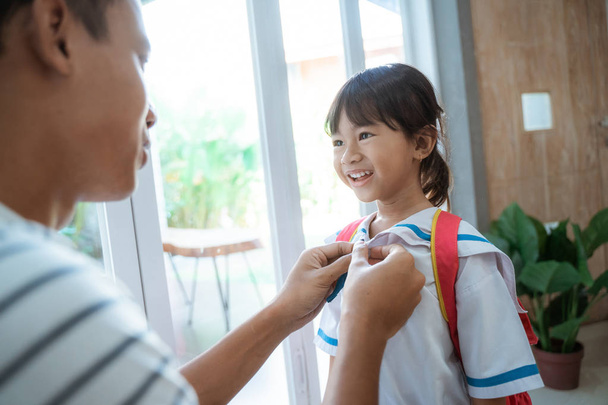 kindergarten student wearing school uniform helped by her father - Φωτογραφία, εικόνα