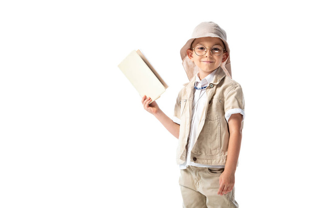 smiling explorer child in glasses holding book and looking at camera isolated on white - Photo, Image