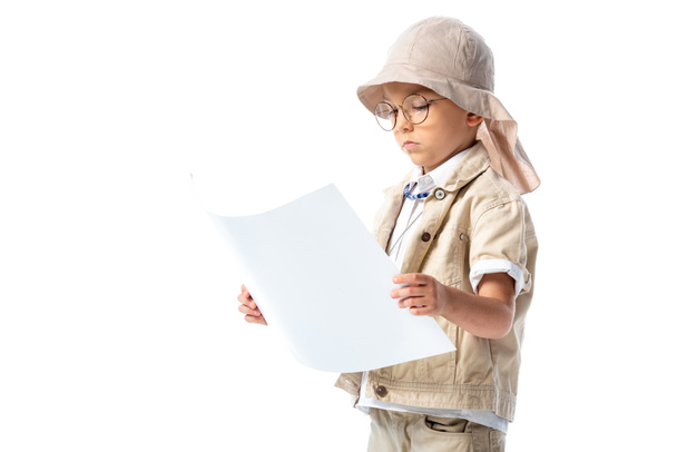 επικεντρωμένος εξερευνητής παιδί σε γυαλιά και καπέλο κοιτάζοντας το πλακάτ απομονώθηκε σε λευκό - Φωτογραφία, εικόνα