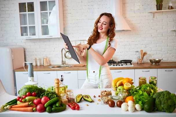 Modern mutfakta yemek yaparken tablet kullanarak genç güzel kadın. Sağlıklı beslenme, vitaminler, diyet, teknoloji ve insan kavramı. Kilo Verme - Fotoğraf, Görsel