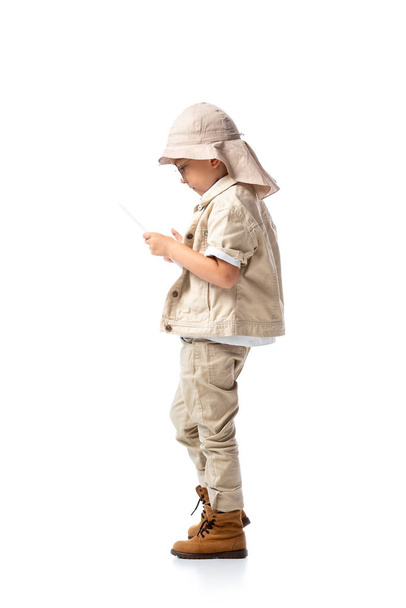 side view of explorer child in glasses and hat using digital tablet isolated on white - Foto, imagen