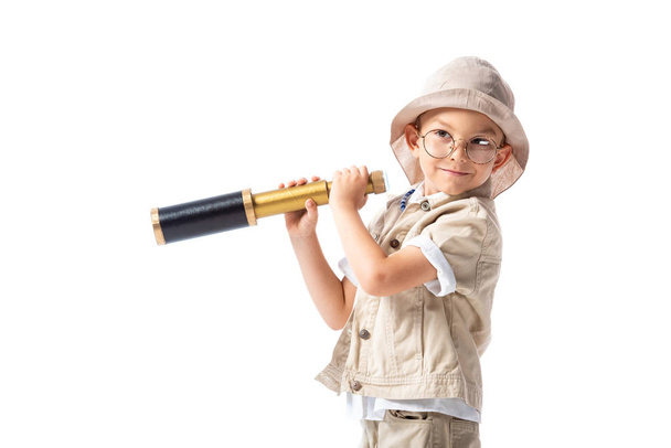 smiling explorer boy in glasses and hat holding spyglass isolated on white - Foto, Bild