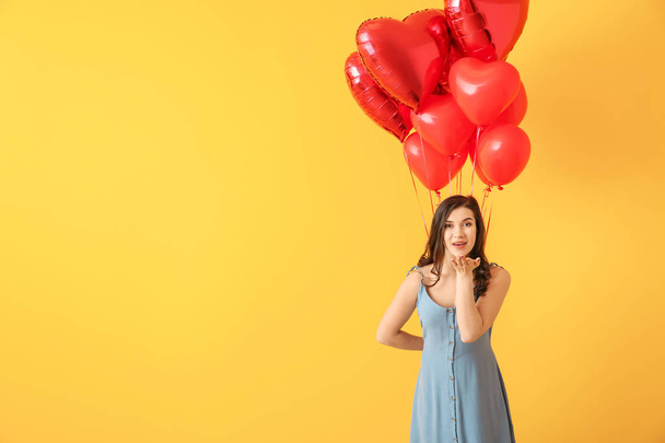 Beautiful young woman with heart shaped air balloons on color background - Photo, Image