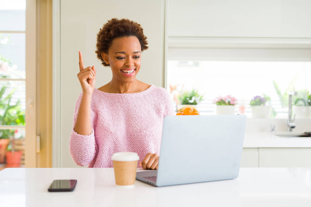 African american Kobieta, pracująca przy użyciu komputer laptop wskazując palcem udany pomysł. Wyszedł i szczęśliwy. Numer jeden. - Zdjęcie, obraz