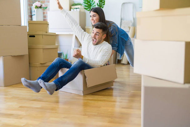 Young couple moving to a new home, having fun riding cardboard b - Photo, Image