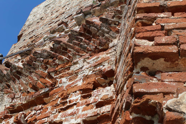 destroyed by time the brick walls of the ancient temple / photo masonry.the wall is ancient, destroyed.red brick.visible metal ties.time has destroyed the Church.ancient ruins of a historic building.against the blue sky.time year summer.day. - Photo, Image