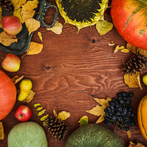 Erntedankfest-Komposition aus Gemüse, Sonnenblumen, Äpfeln und Herbstblättern auf Holzgrund. flache Lage, Draufsicht. - Foto, Bild