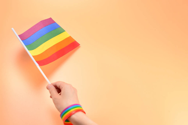 Bandeira LGBT na mão da mulher no fundo laranja. Espaço de cópia
.  - Foto, Imagem