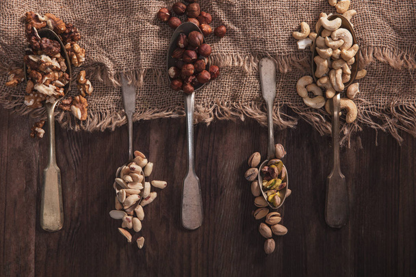 Different types of nuts on old spoons - Fotoğraf, Görsel