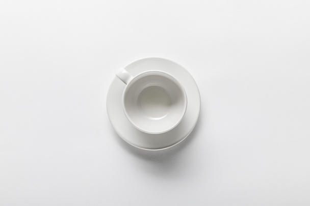 top view of empty white cup on saucer on white background - Fotografie, Obrázek