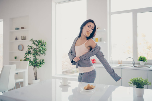 Close up side profile photo beautiful she her lady hot beverage croissant dessert inside mouth late job dressing jacket blazer exhausted formal-wear checkered plaid costume bright kitchen indoors - Photo, Image