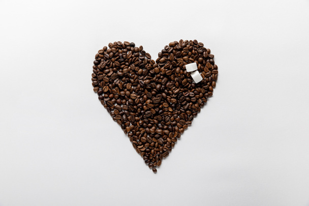top view of heart made of coffee grains with sugar on white background - Photo, image