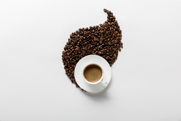 pohled na kávu v šálku blízko listů z kávových zrn na bílém pozadí - Fotografie, Obrázek